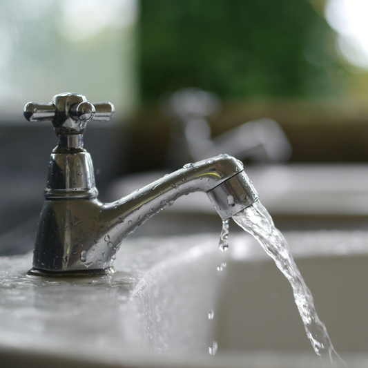 Ein Wasserhahn mit fließendem Wasser, das die schädlichen Auswirkungen von hartem Wasser auf Haut und Haare symbolisiert.